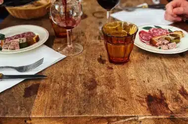 Ambiance conviviale autour d’un déjeuner dans un bouchon lyonnais, charcuterie et vin rouge à table.